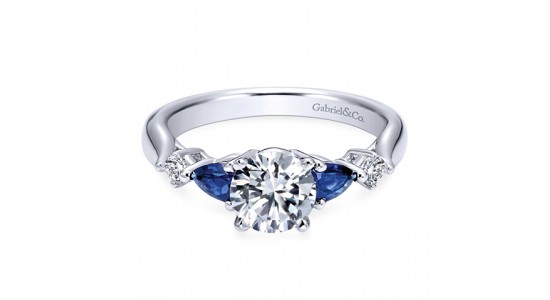 a silver toned engagement ring with a round cut diamond and sapphire side stones