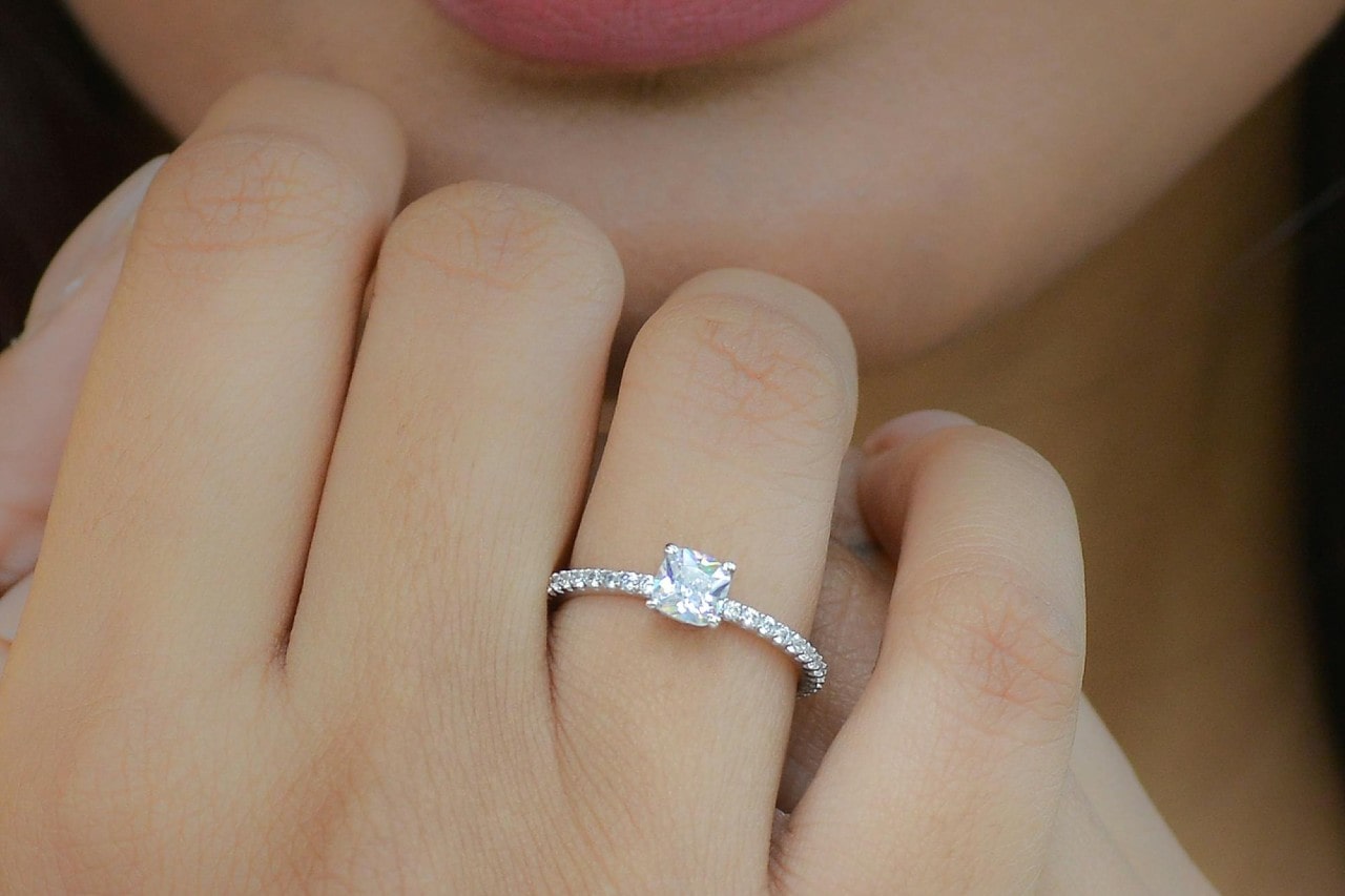 a woman’s hand held up to her chin, adorned with a princess cut engagement ring