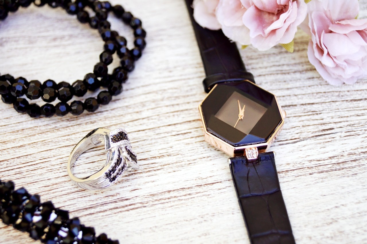 a watch with an octagonal shape on a table next to flowers and jewelry