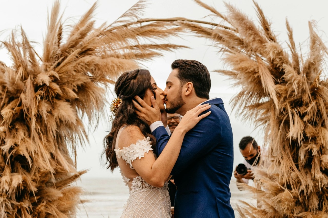 A bride and groom kissing at their fall-themed altar on the beach.