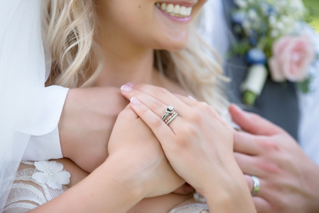 a groom embraces his bride, showing her bridal stack.