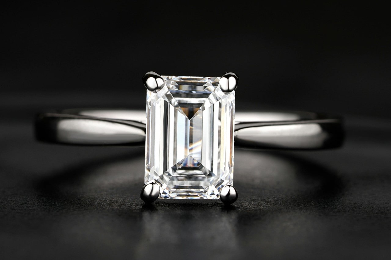 a white gold solitaire engagement ring with an emerald cut center stone