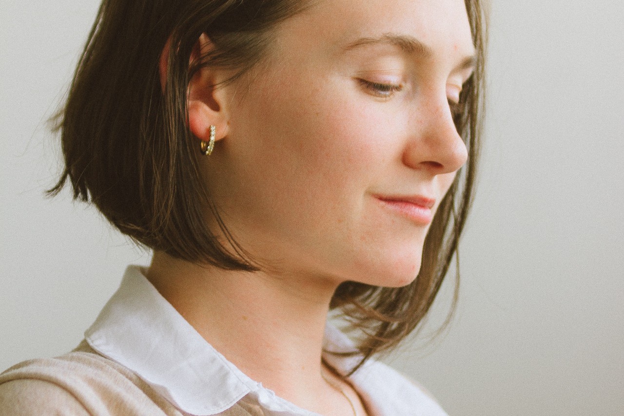 Young woman wearing a golden hoop earring made out of yellow gold