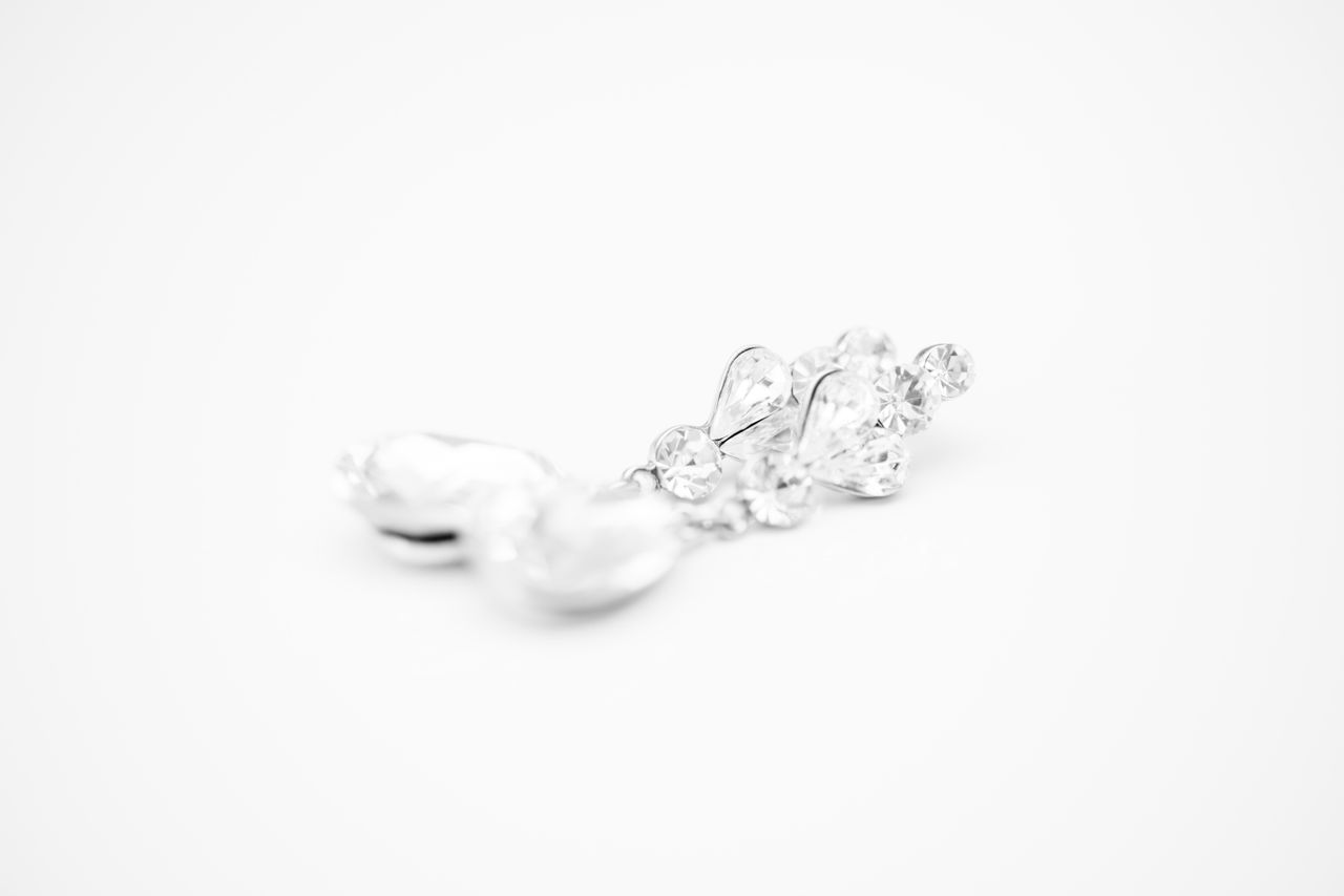 A diamond encrusted earring with a pearl on white background