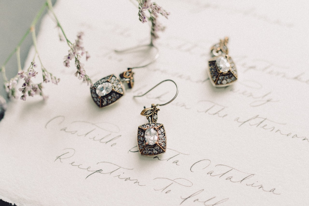 A close-up of diamond earrings and a matching pendant on a handwritten note.