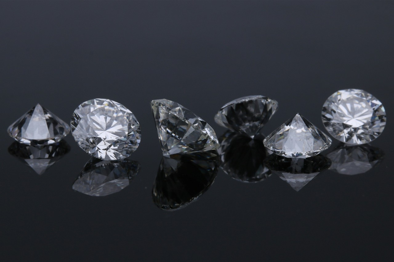 several diamonds in a row on a reflective black background