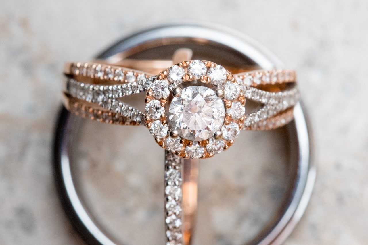 A close-up of a stunning halo engagement ring displayed with two wedding bands.