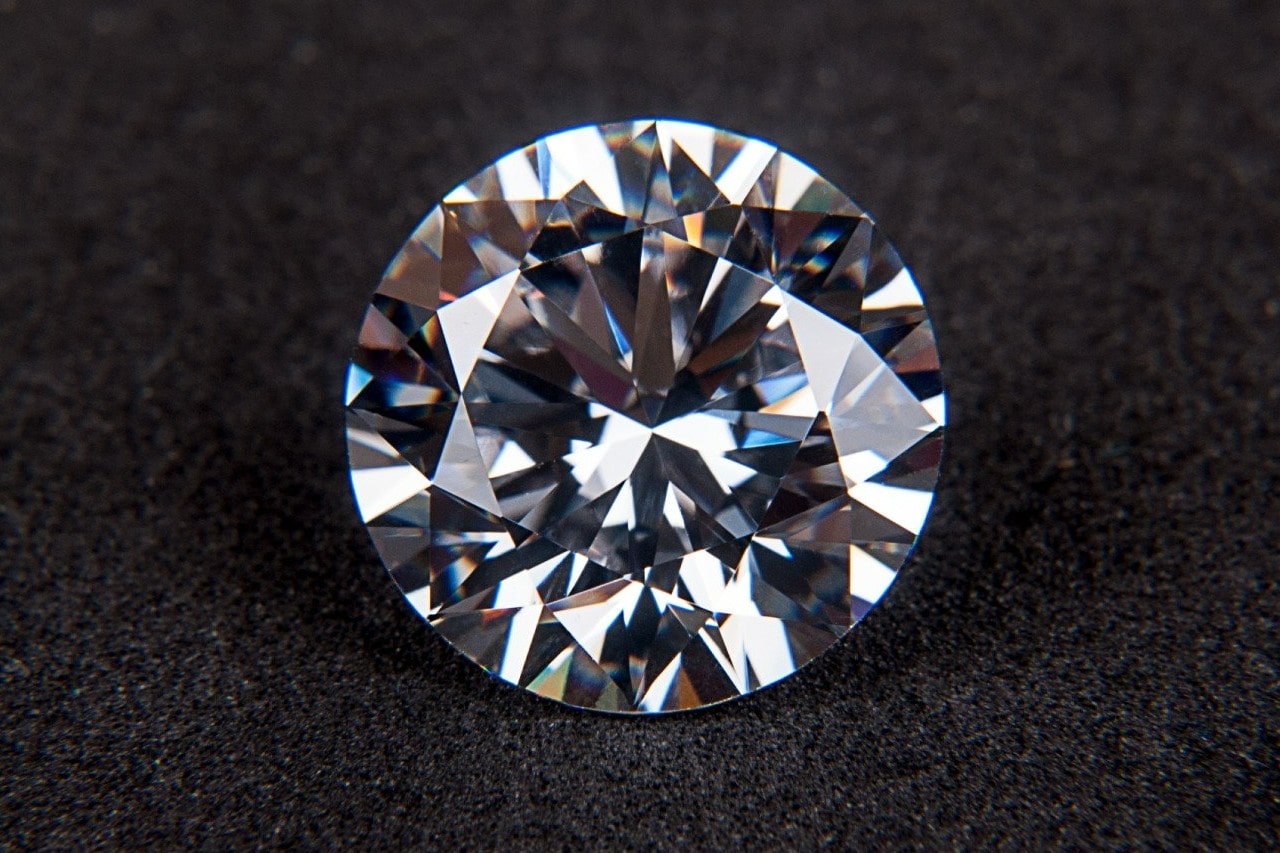 A close-up of a stunning round-cut diamond on a soft black background.