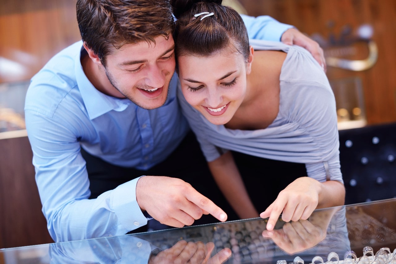 A happy young couple looking at rings at their local fine jewelry store.