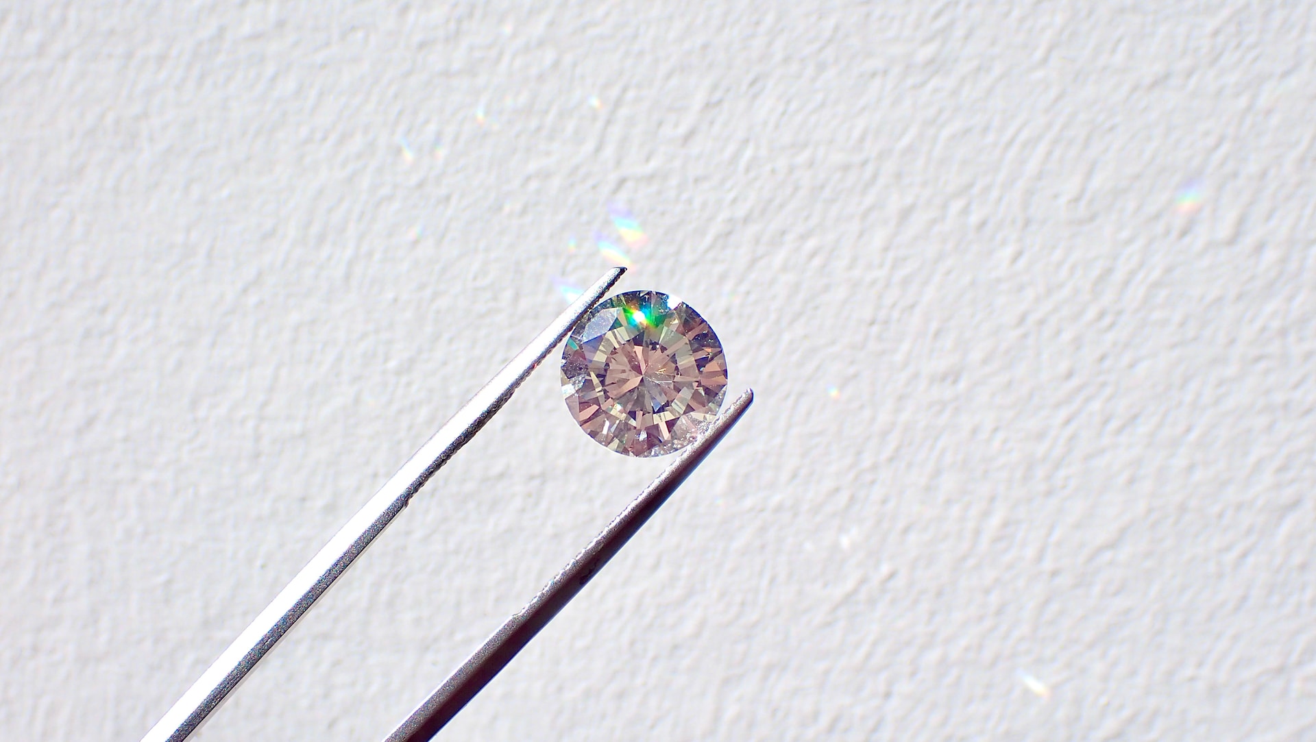 a pair of tweezers holding a round cut diamond